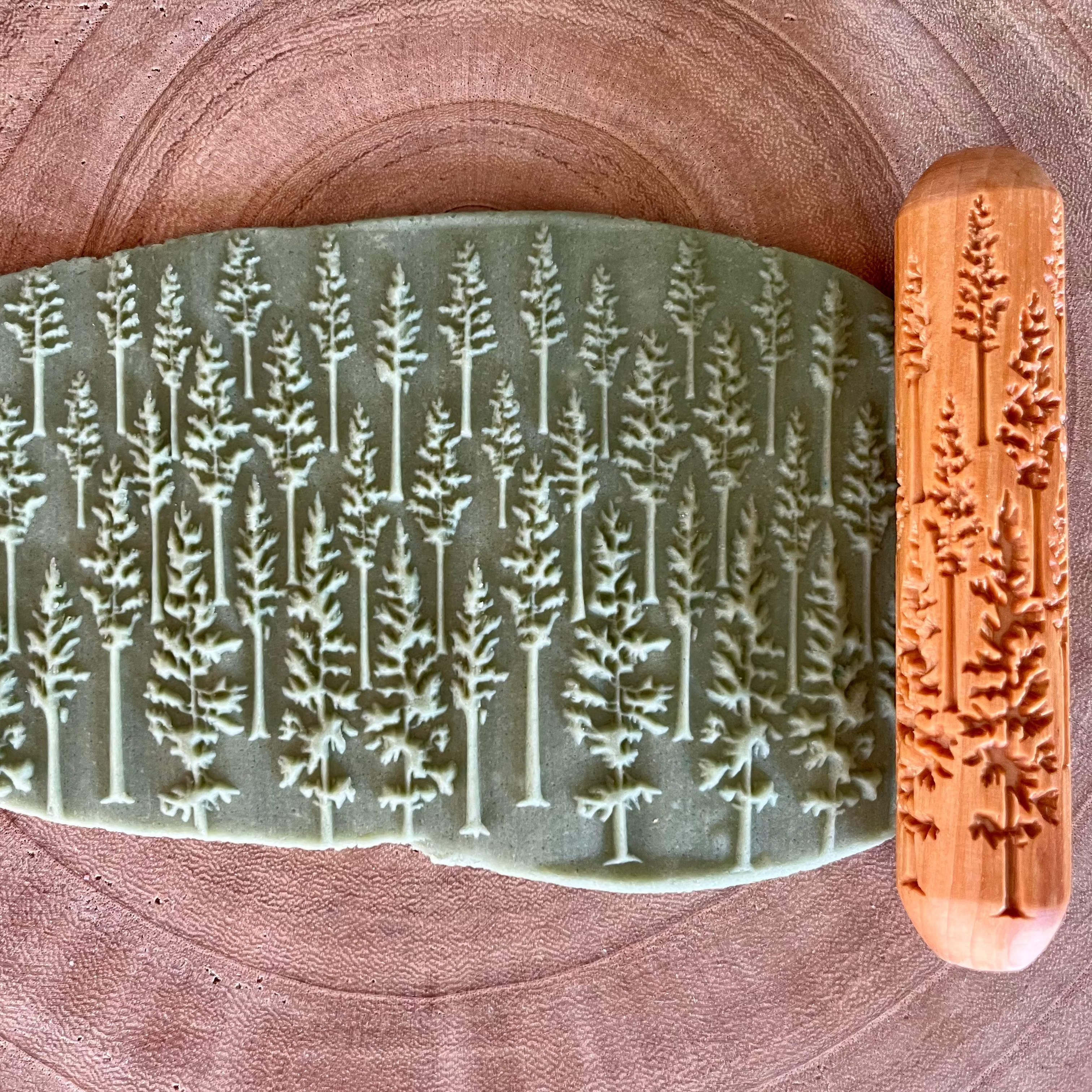 large tree patterned wooden roller rolled along soft handmade green playdough